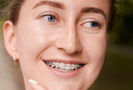 Young person smiling brightly, displaying healthy straight teeth after orthodontic treatment.