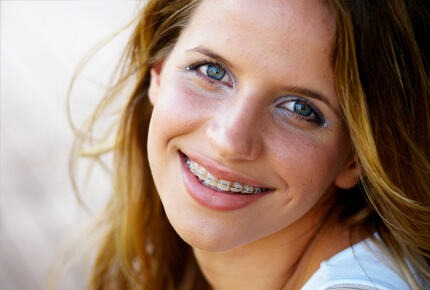 Woman with reddish-brown hair smiling at camera in professional headshot style photo.