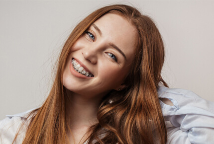 Woman with reddish-brown hair smiling warmly at camera in studio setting.