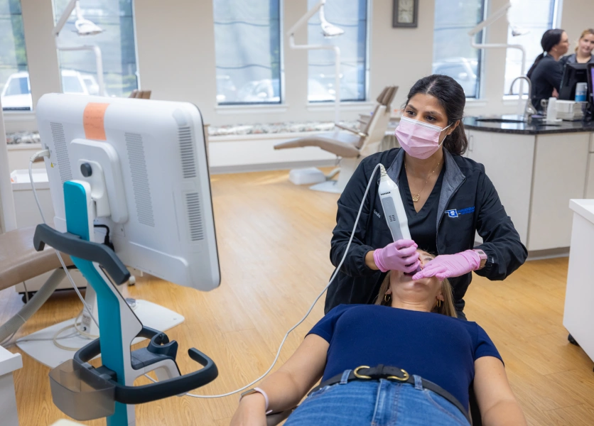 Orthodontist in mask examines patient's teeth in modern dental clinic treatment room.