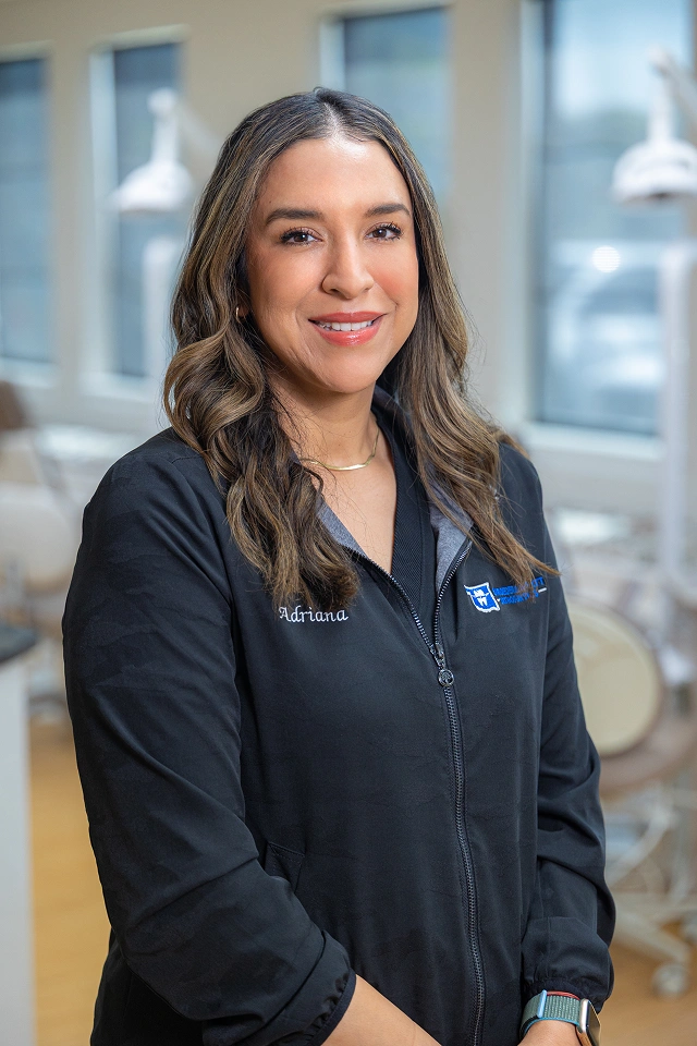 Professional orthodontist in dark scrubs smiling in modern clinical office setting