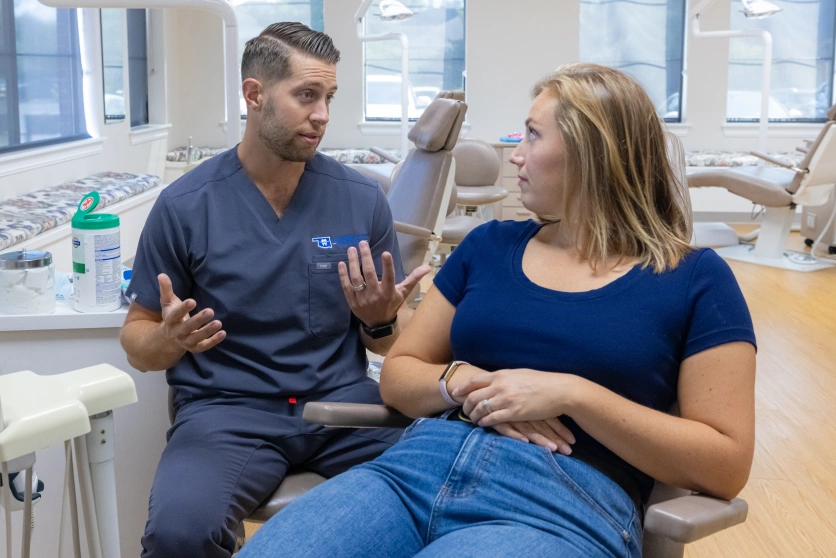 Orthodontist discussing treatment plan with female patient in dental office consultation room.