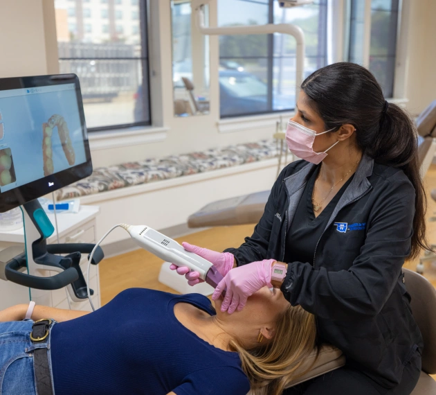 Orthodontist in mask and gloves examining patient's teeth in modern dental office.